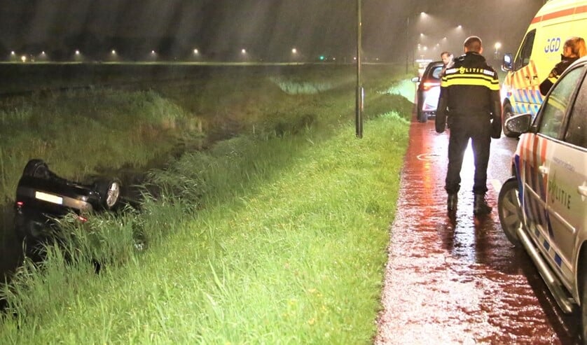 De auto ligt op z'n kop in de sloot langs de weg (foto: Nick v.d. Toorn/Regio15).