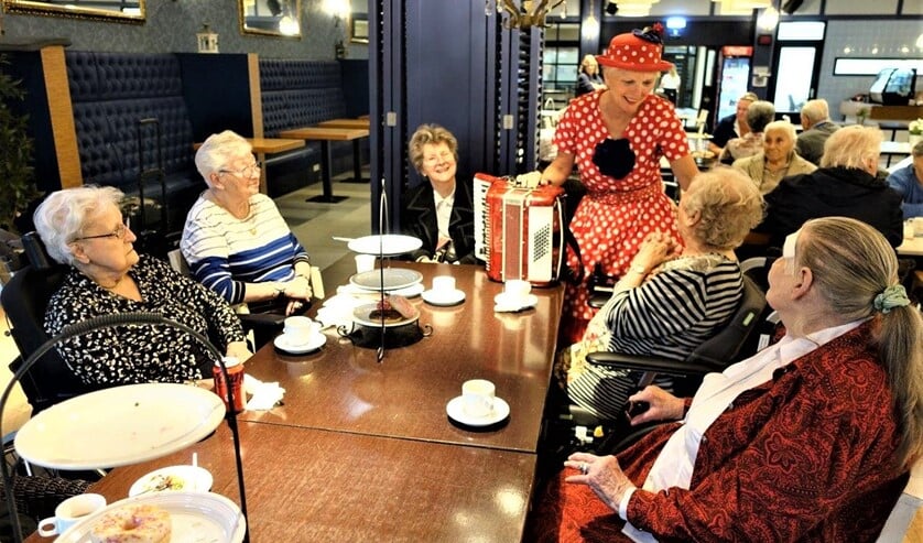 <p> Een clownesk aangeklede vrouw speelde op een accordeon liedjes waarbij bewoners konden meezingen (foto: Ap de Heus). </p>