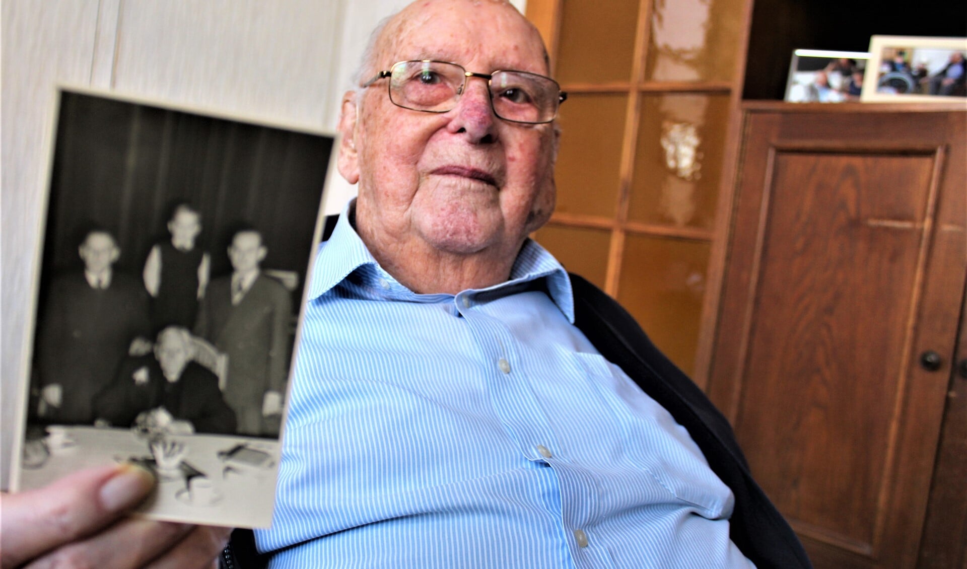 De heer Groenewegen toont een foto met daarop (zittend) zijn grootvader die ook 100 jaar oud werd (foto: Dick Janssen).