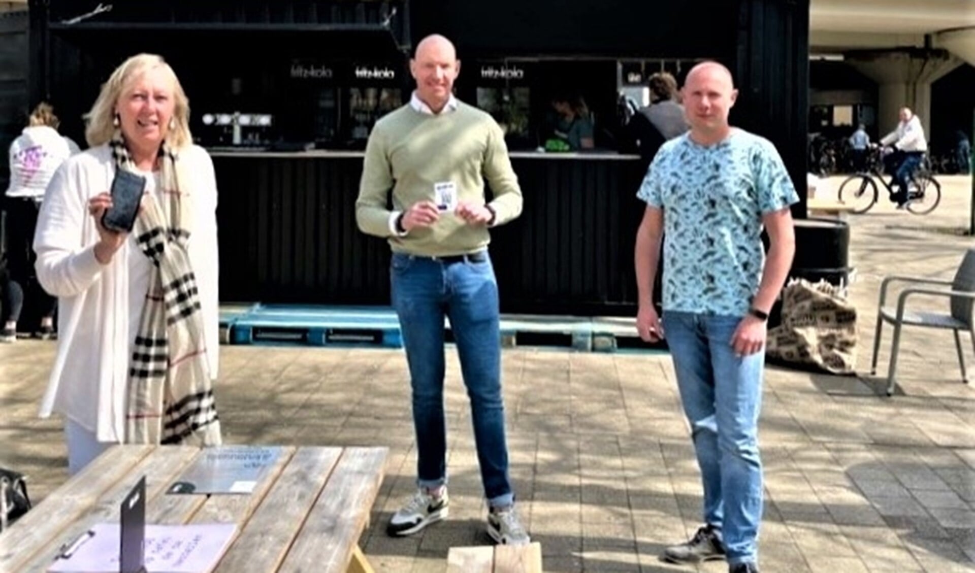 Wethouder Astrid van Eekelen toont app met de horecaondernemers Ricardo Houtman en Eddy Knopjes op Stationsplein (foto: gemeente).