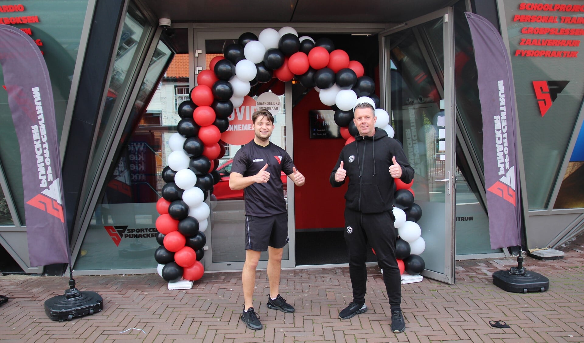Dave Nijhuis en zijn collega Gerald Lagrand onder de ballonnenboog bij de entree van Sportcentrum Pijnacker.