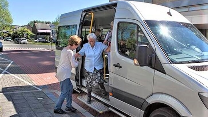 Een vrijwilliger van Bus 47 helpt een passagier de bus uit (foto: pr Woej).
