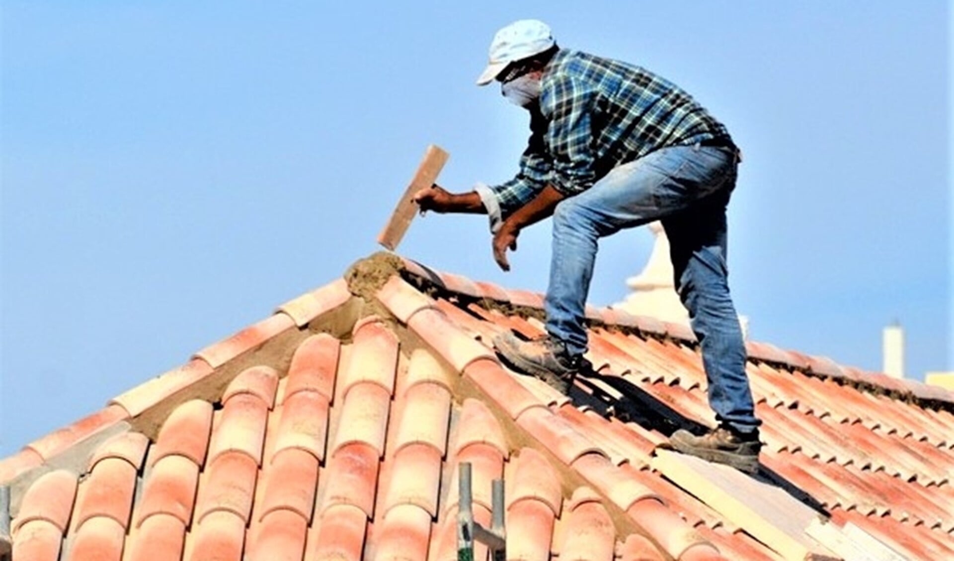 Oplichters bieden bijvoorbeeld werkzaamheden aan het dak aan (stockfoto van onbekend persoon die werk op een dak verricht). 