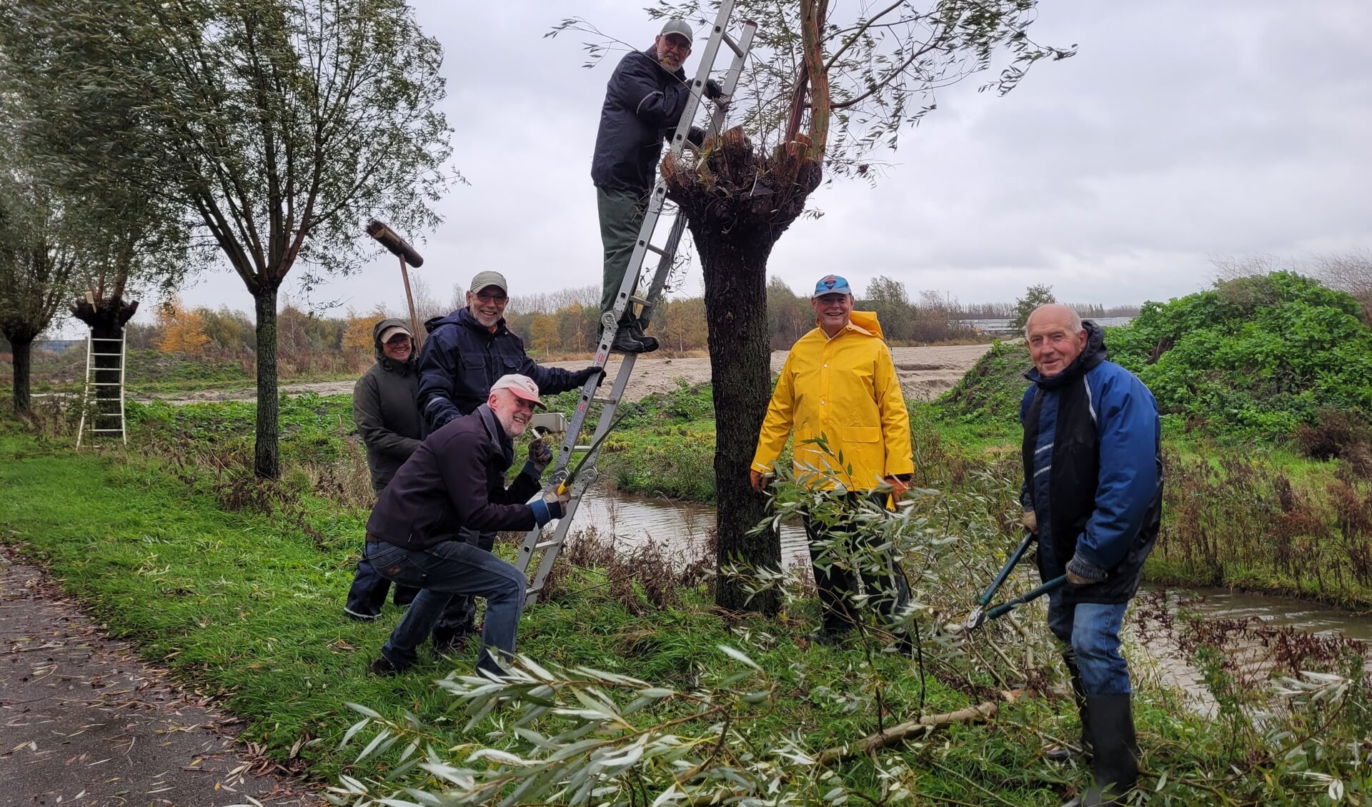 Peter Wienbelt houdt te midden van zijn mede-vrijwilligers de ladder vast.