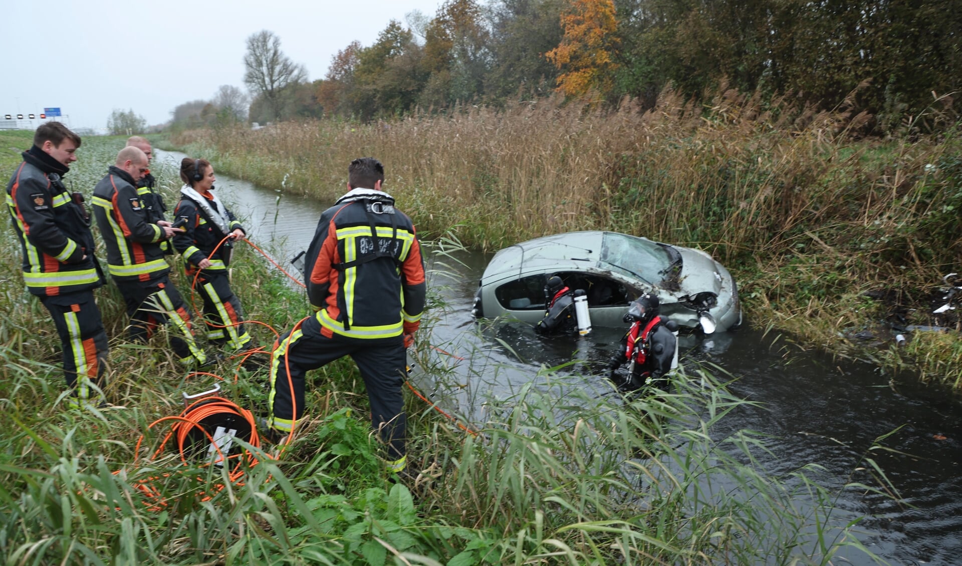 Brandweerlieden en -duikers helpen bij de berging van het voertuig waarbij niemand werd aangetroffen (foto: Rene Hendriks Regio15).
