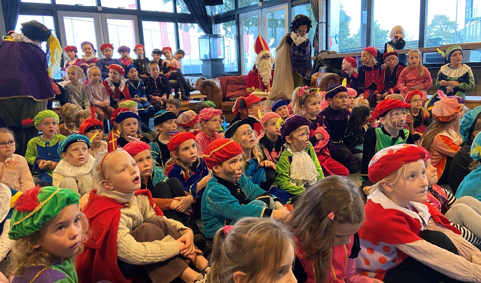Kinderen kijken knus bij elkaar naar De Club Van Sinterklaas en het Vergeten Pietje.