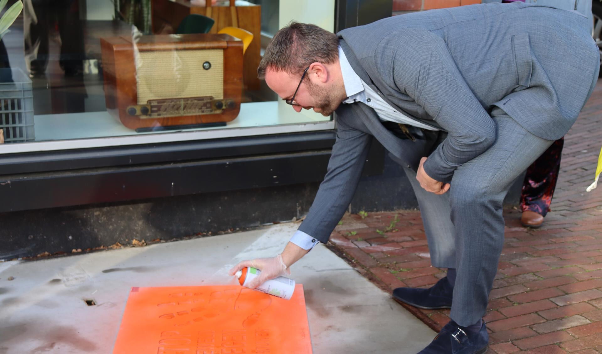 Wethouder Bouke Velzen spuit het logo van Orange the world.