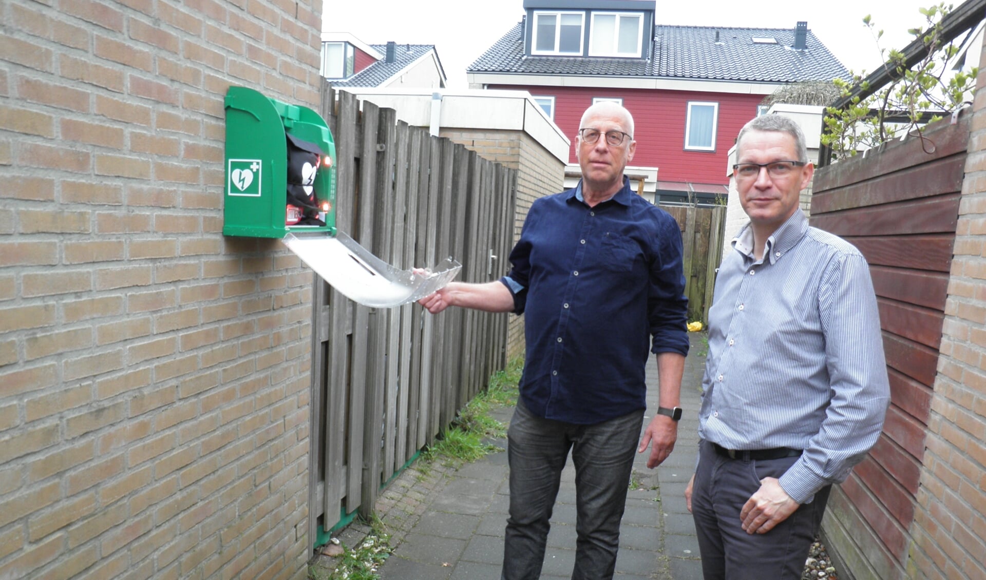 Rob Schaafsma (l) en Marco de Bruin tonen de AED aan de achterkant van de woning van Jonagoldhof 4 in de buurt De Boomgaard. Foto Kees van Rongen