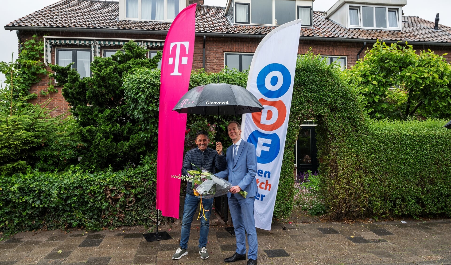 Wethouder Jan-Willem Rouwendal (rechts op de foto) feliciteert de heer Raimondi dat hij als eerste inwoner in Leidschendam kan gebruikmaken van het supersnelle glasvezel (foto Michel Groen).