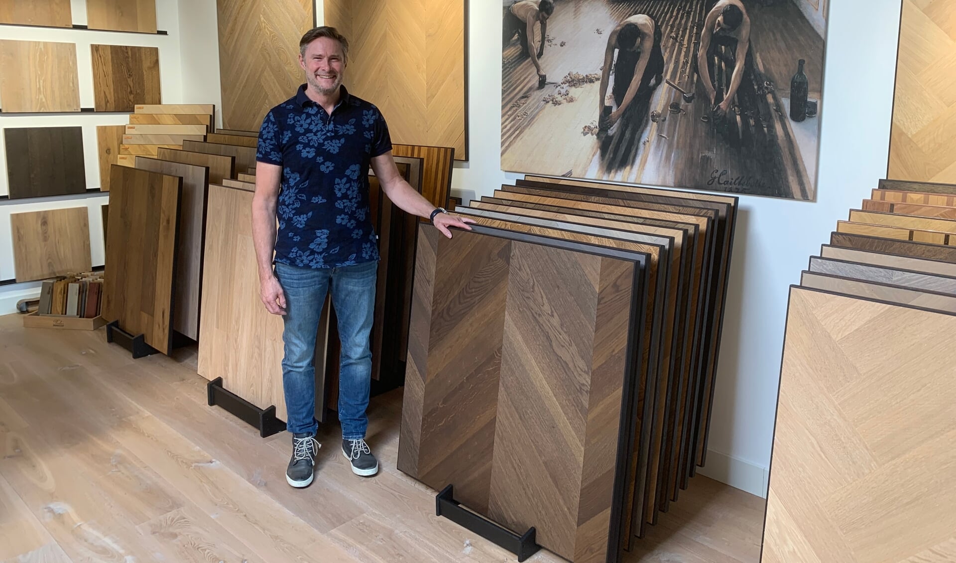 John Leijte in zijn showroom. Op het schilderij vakmannen uit vroeger tijden.