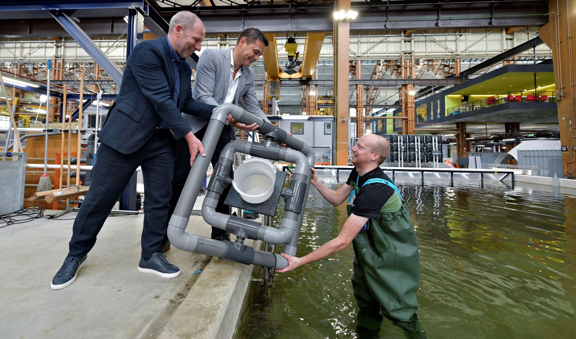 Onderzoeker en aquarist Sander van Lopik toont het drijvende kweeksysteem aan zijn directeur Erik Zevenbergen (links) en Richard van der Eijk (Havenbedrijf).