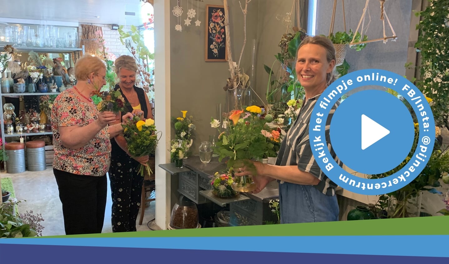Ellen de Hoog met een boeket en op de achtergrond Ingrid Hutink die vaste klant Elly Teerling (links) helpt.