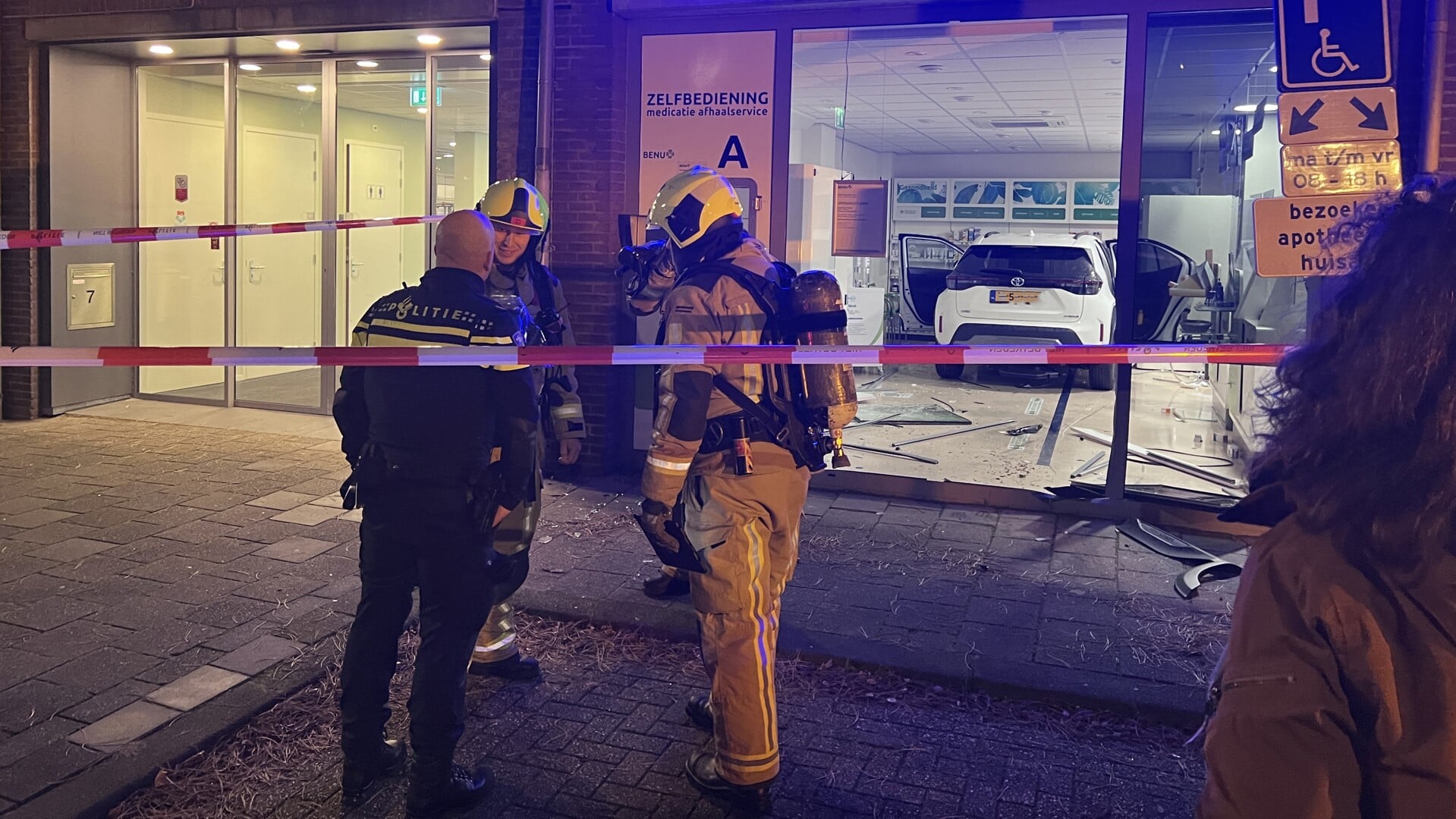 De personenauto staat achterin de apotheek, terwijl de brandweer en politie onderzoek doen (foto: Rene Hendriks).