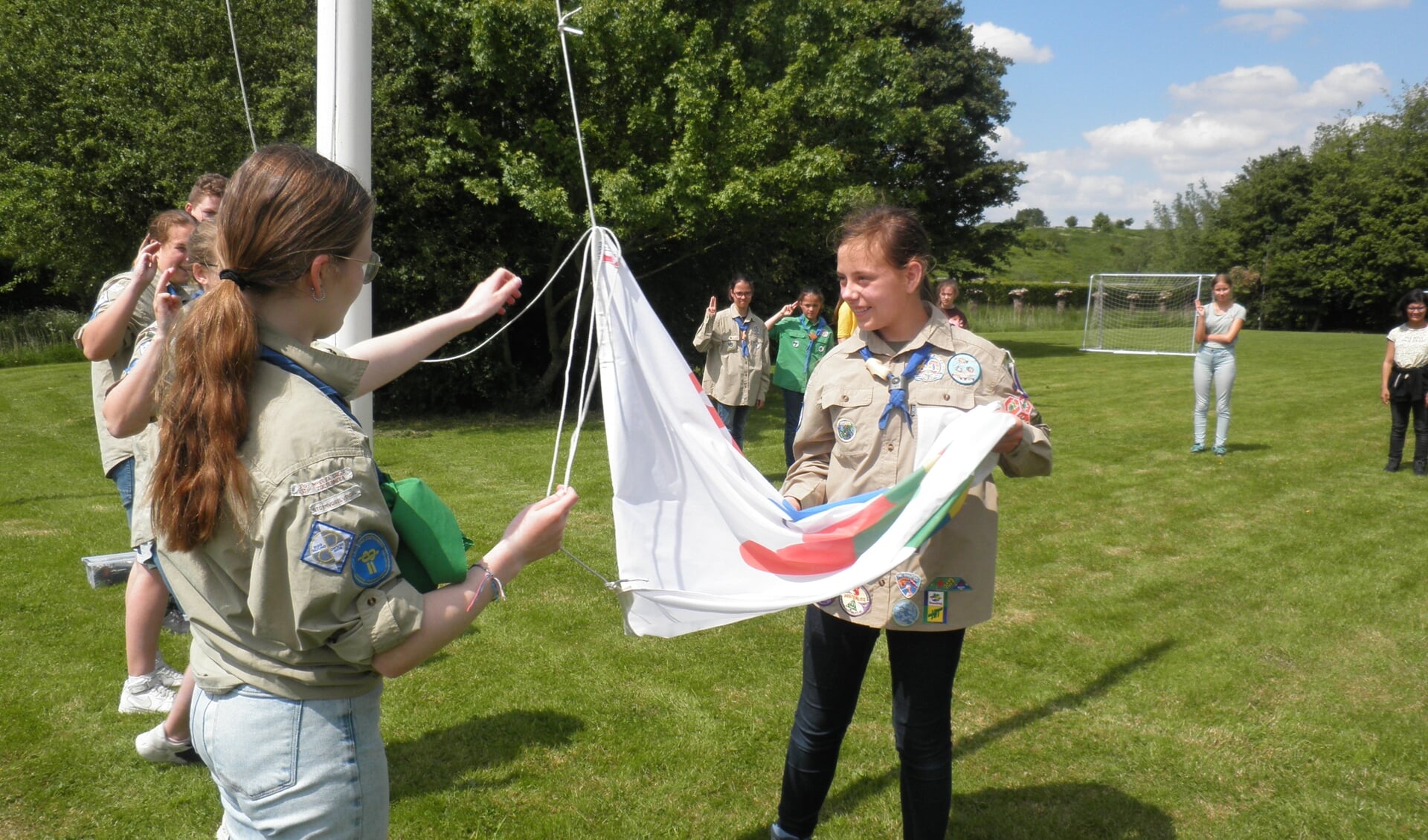 Lindy (links) en Aleid hijsen de vlag bij de opkomst zaterdagmiddag op het terrein van Scouting Impeesa. Foto Kees van Rongen 