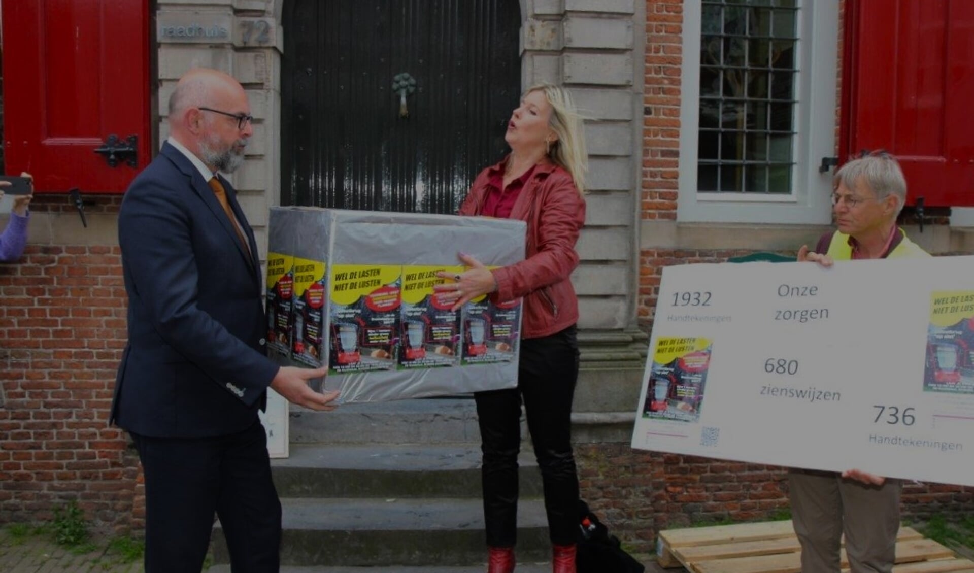 Burgemeester Martijn Vroom krijgt een pak vol zorgen en handtekeningen overhandigd na afloop van de protestmars (foto: Ap de Heus).