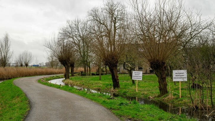 De borden die niet mochten ‘deelnemen’ aan de vergadering, staan nu in een weilandje vlakbij het natuurgebied Ackerdijk ‘hun mening te geven’.