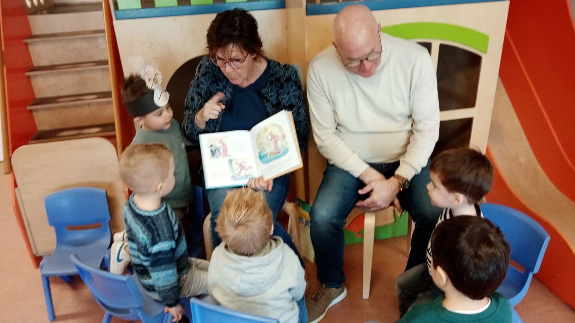Kinderen luisteren aandachtig naar de voorlezende opa en oma.