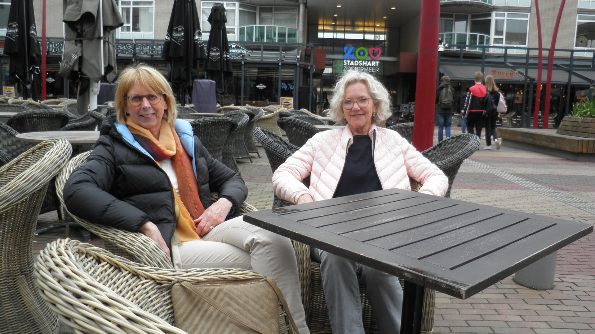 Vriendinnen Desiree Verzantvoort en Toine Tonies op een verlaten terras op het Stadhuisplein: “Dat is bij het Koningsontbijt wel anders.” (foto: Kees van Rongen).