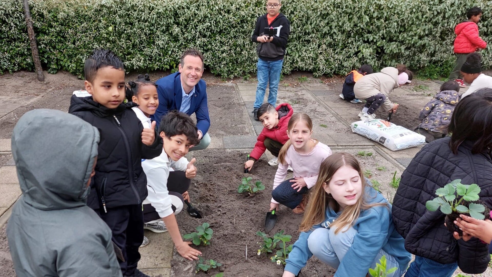 Wethouder Marcel Belt bij De Driemaster in de schooltuinmet leerlingen die zaaien en planten (foto: pr). 