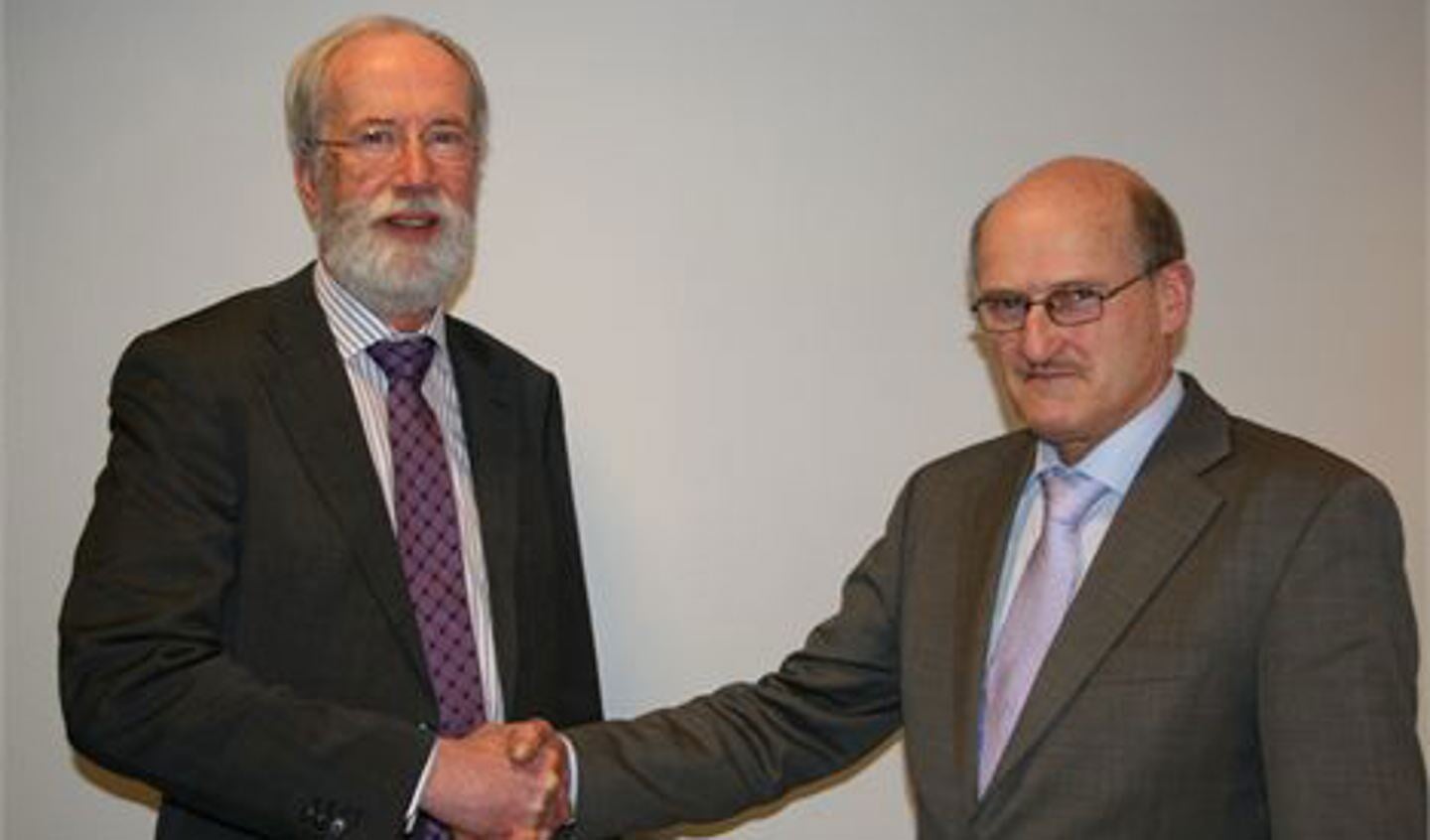 Wethouder Jaap van Staalduine en hoogheemraad Arie van den Berg schudden elkaar de hand na de ondertekening.