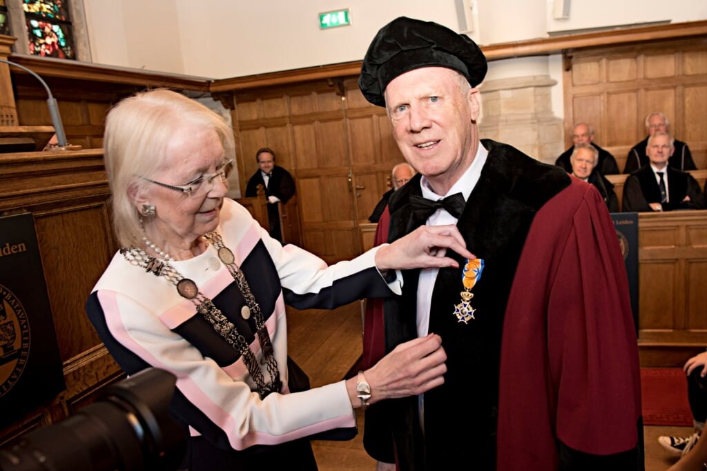 Burgemeester Ravestein speldt het lintje hoogstpersoonlijk op in het academiegebouw in Leiden. (Foto: Cok van den Berg)