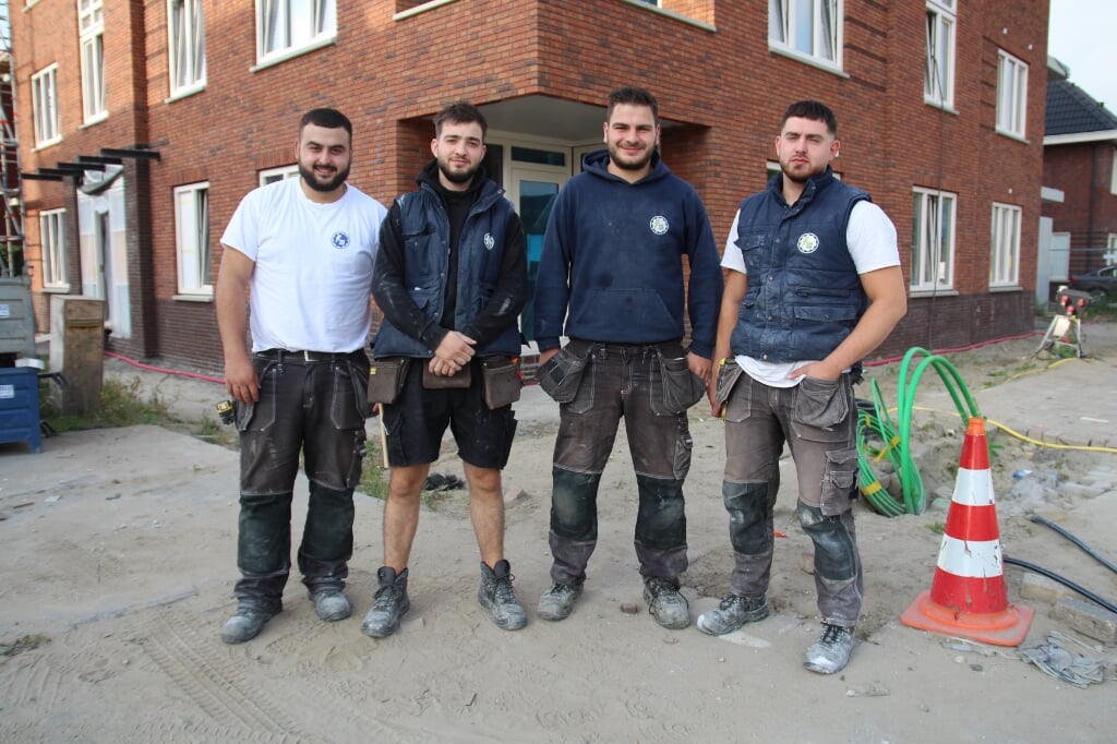 Halil, Mustafa, Ömer en Enes met op de achtergrond een van de appartementengebouwen waar ze aan het werk zijn.
