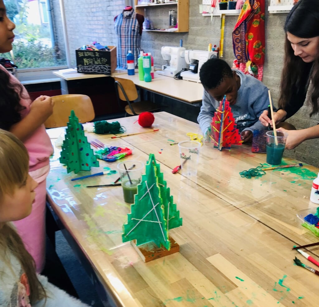 Kinderen van de taalklas van De Regenboog hebben houten jerstbomen gemaakt en versierd.