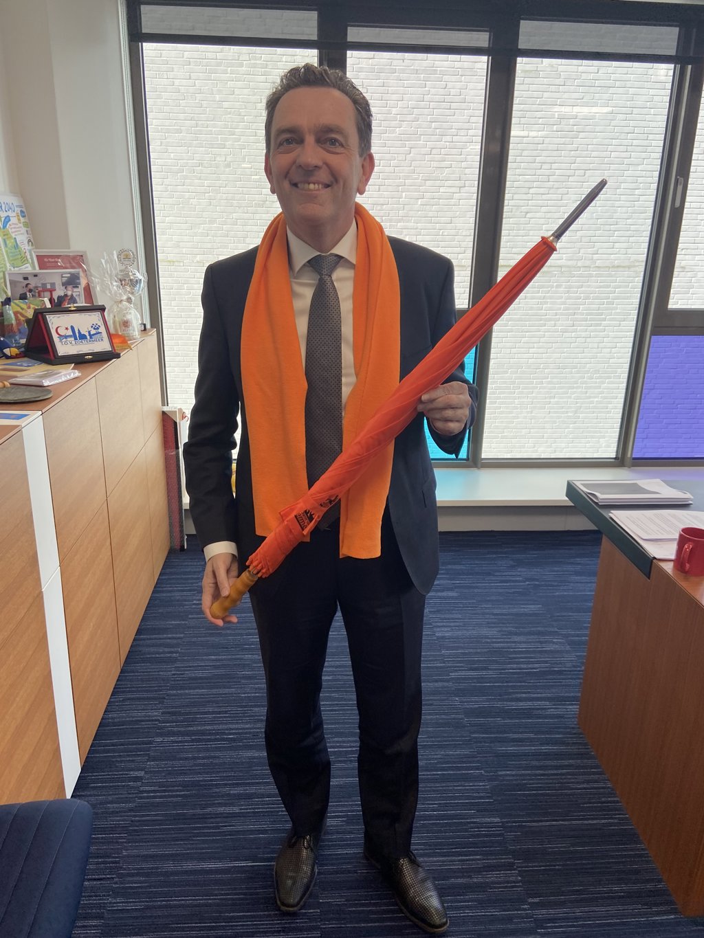 Burgemeester Bezuijen krijgt oranje paraplu voor het geval het gaat regenen.