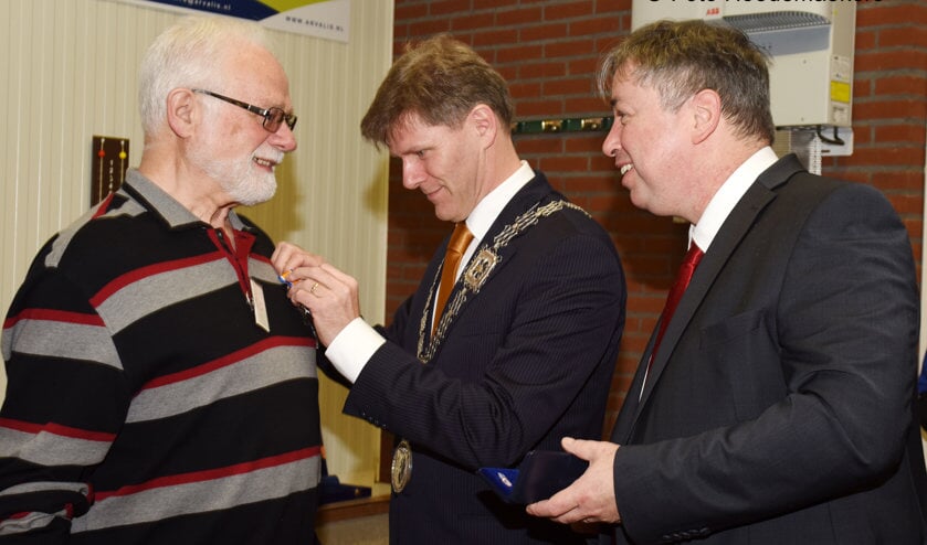 Locoburgemeester Jan Loonen speldt de onderscheiding op. Rechts gedeputeerde Patrick van der Broeck. Foto: Hoedemaekers Venray.