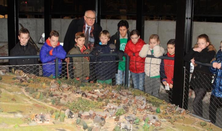 Burgemeester Van Soest van de gemeente Boxmeer met een groep leerlingen van een basisschool uit Boxmeer, bij een maquette van het in 1944 verwoeste Overloon.
