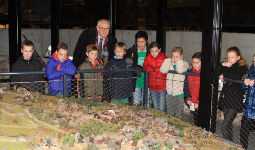 Burgemeester Van Soest van de gemeente Boxmeer met een groep leerlingen van een basisschool uit Boxmeer, bij een maquette van het in 1944 verwoeste Overloon.