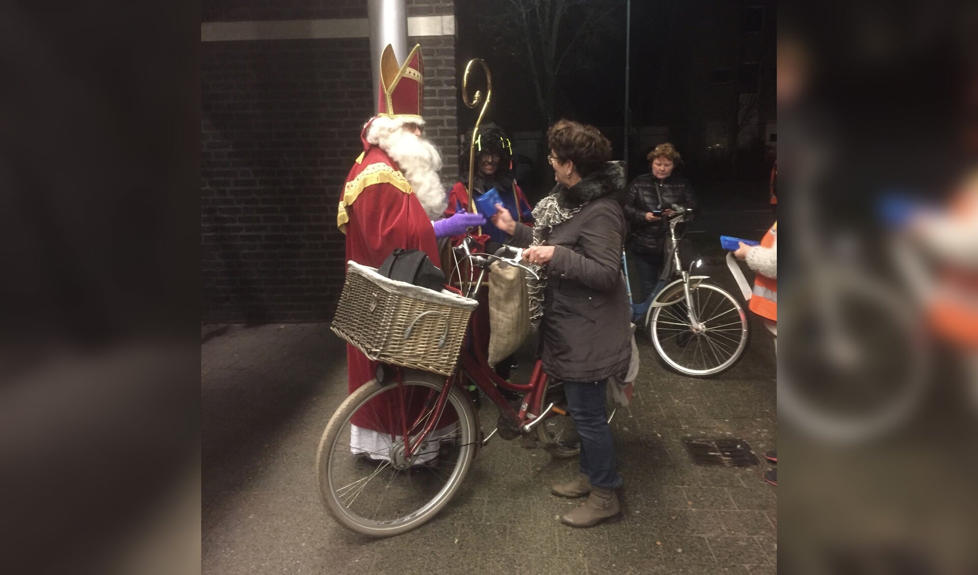 Sinterklaas verrast een fietsster met een VVV-bon. 