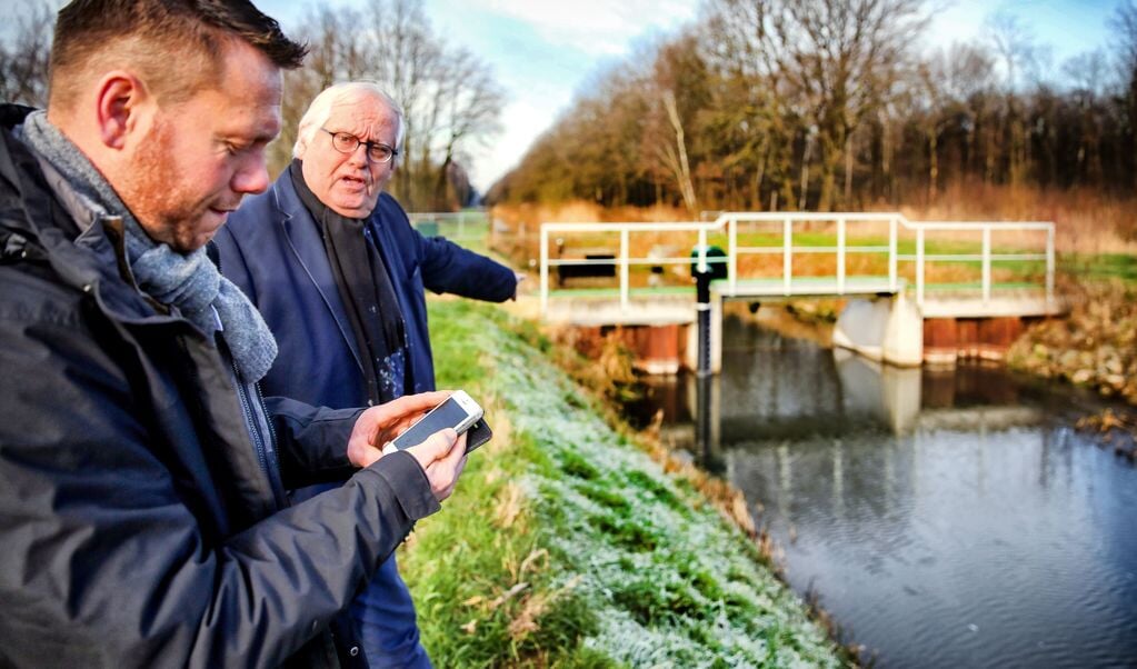 Waterschapsvoorzitter Jan Schrijen (rechts) en melkveehouder Jakob Pustjens bekijken het peil in de Rosveldlossing (Nederweert).
