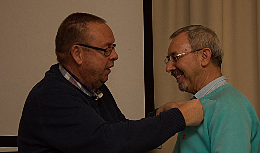 Voorzitter Peter Teeuwen speldt de zilveren HPV-speld op bij scheidend bestuurslid Jan Strijbos. Foto: Pie Noten.
