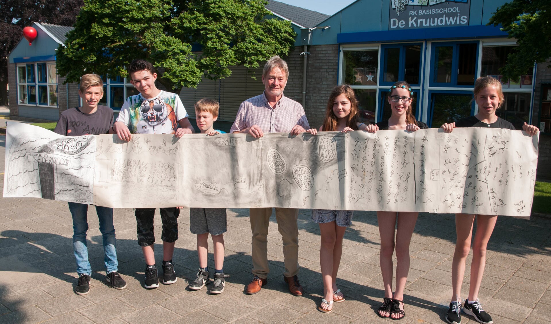 Martin Arens toont samen met leerlingen van De Kruudwis de bijzondere tekening. Foto: Lotte Kamphuis. 