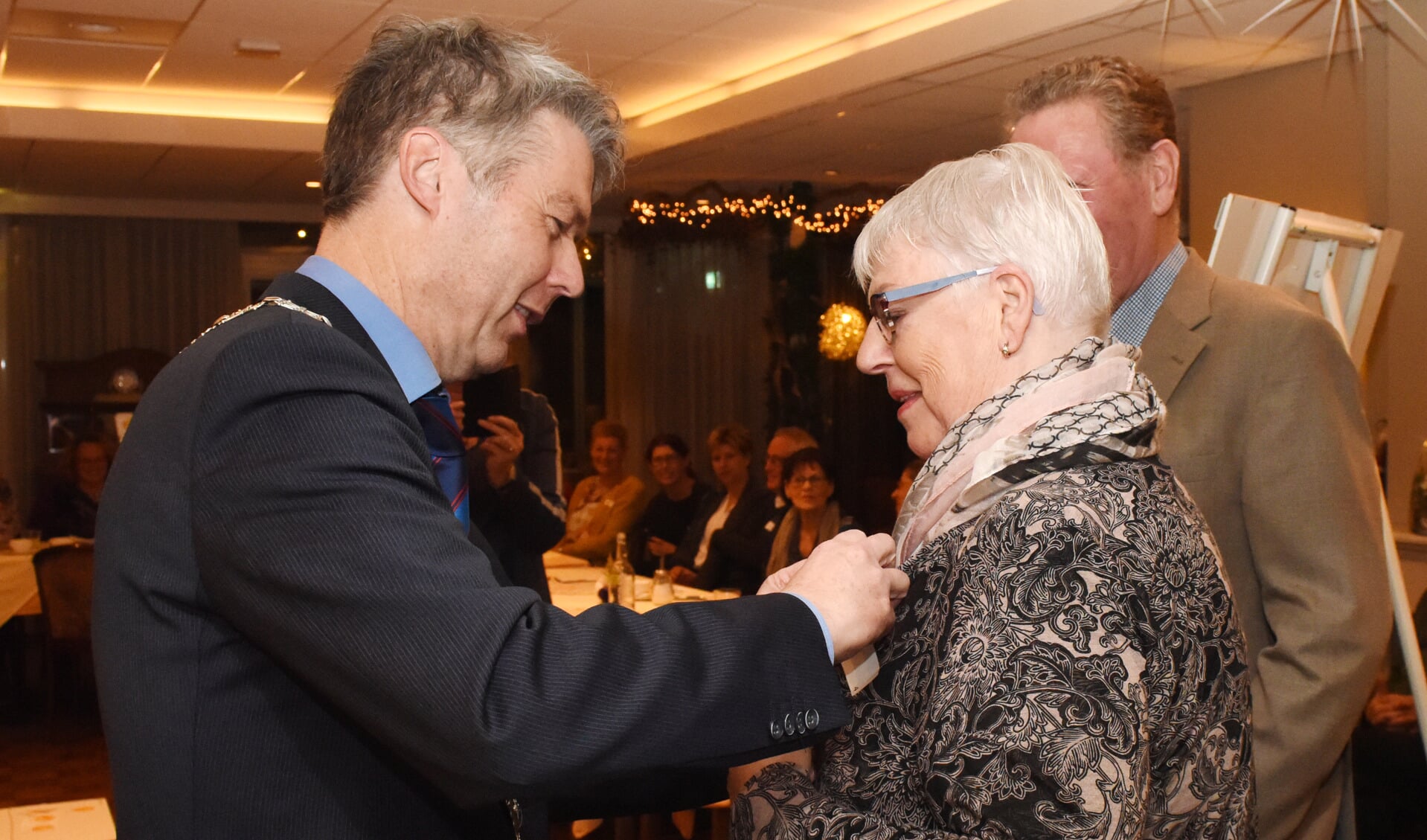 Burgemeester Hans Gilissen speldt Jeanne Hendrix de onderscheiding op. Foto: Hoedemaekers Venray. 