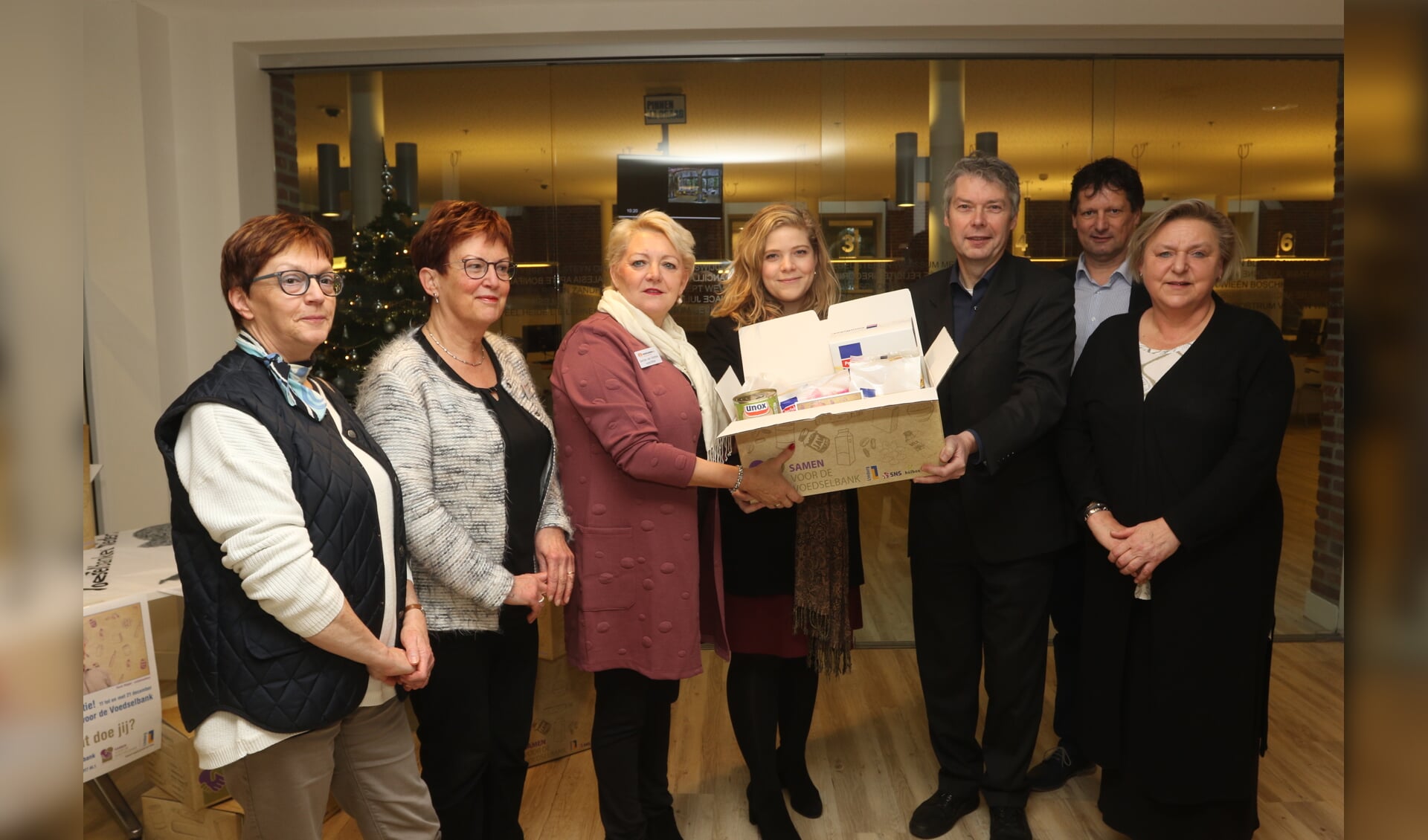 Gerda van Stelten krijgt het eerste voedselpakket uit handen van wethouder Anne Thielen en burgemeester Hans Gilissen.