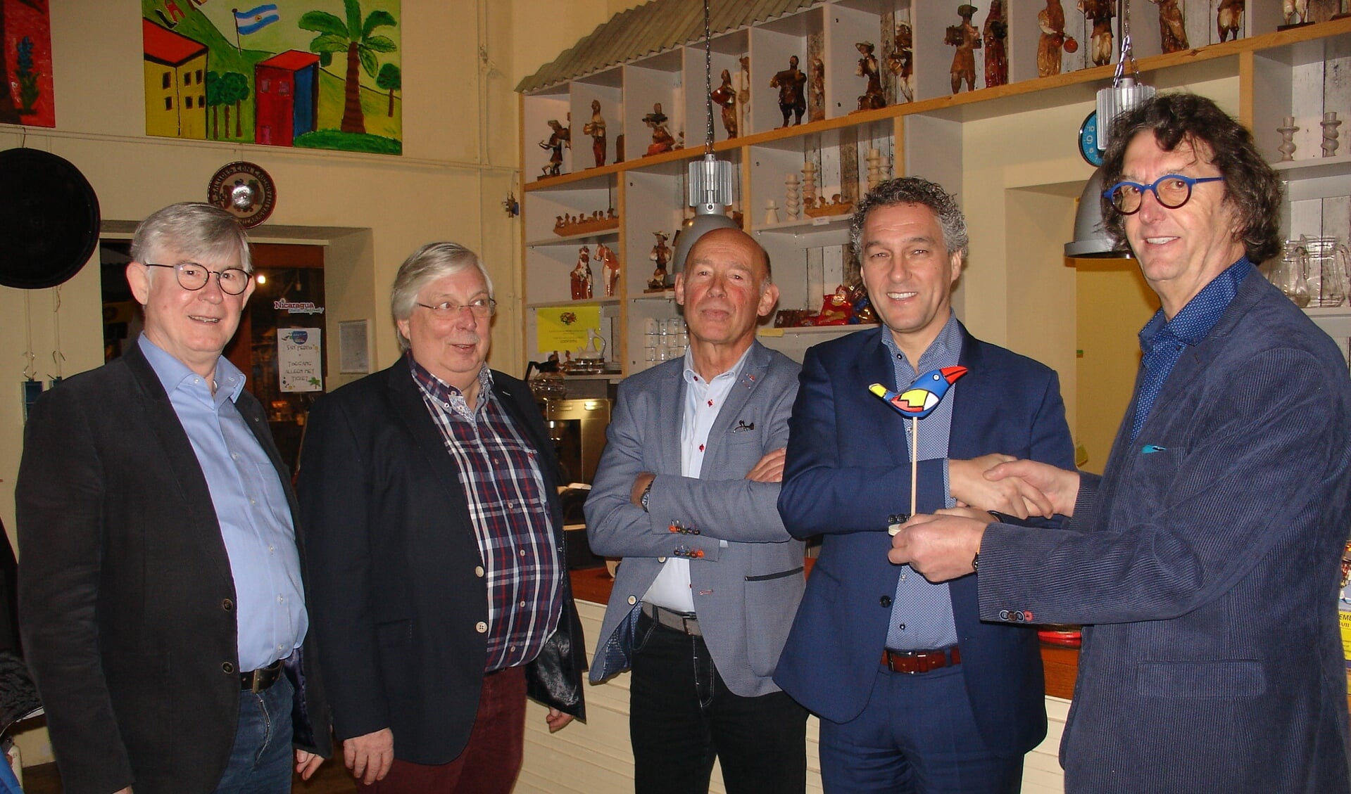  Hans Teunissen ontvangt van voorzitter René Poels de kleurrijke mascotte van het Wereldpaviljoen.