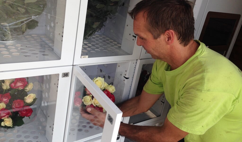 Twan Reintjes zet verse bloemen in de nieuwe automaat. 