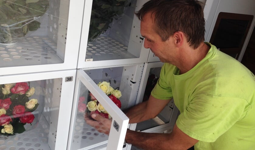 Twan Reintjes zet verse bloemen in de nieuwe automaat.