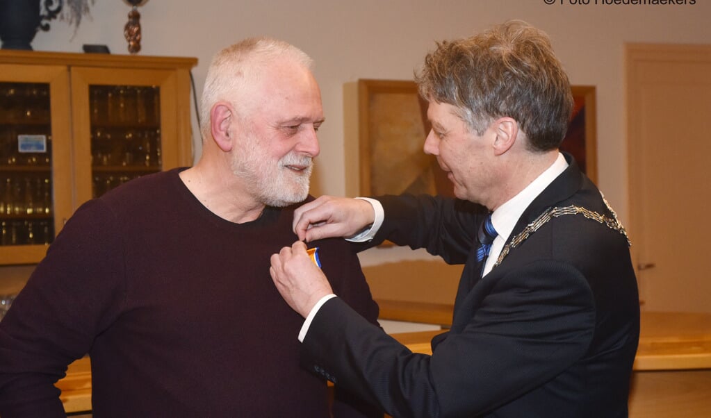 Burgemeester Hans Gilissen speldt Theo Zegers de onderscheiding op. Foto: Hoedemaekers.