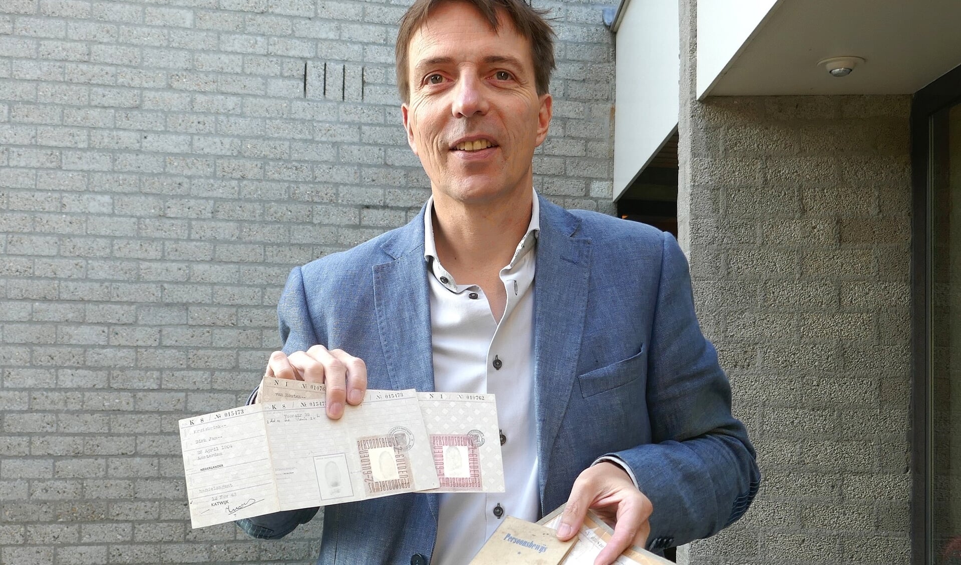 Erik van den Dungen toont een aantal persoonsbewijzen uit de collectie van het museum.