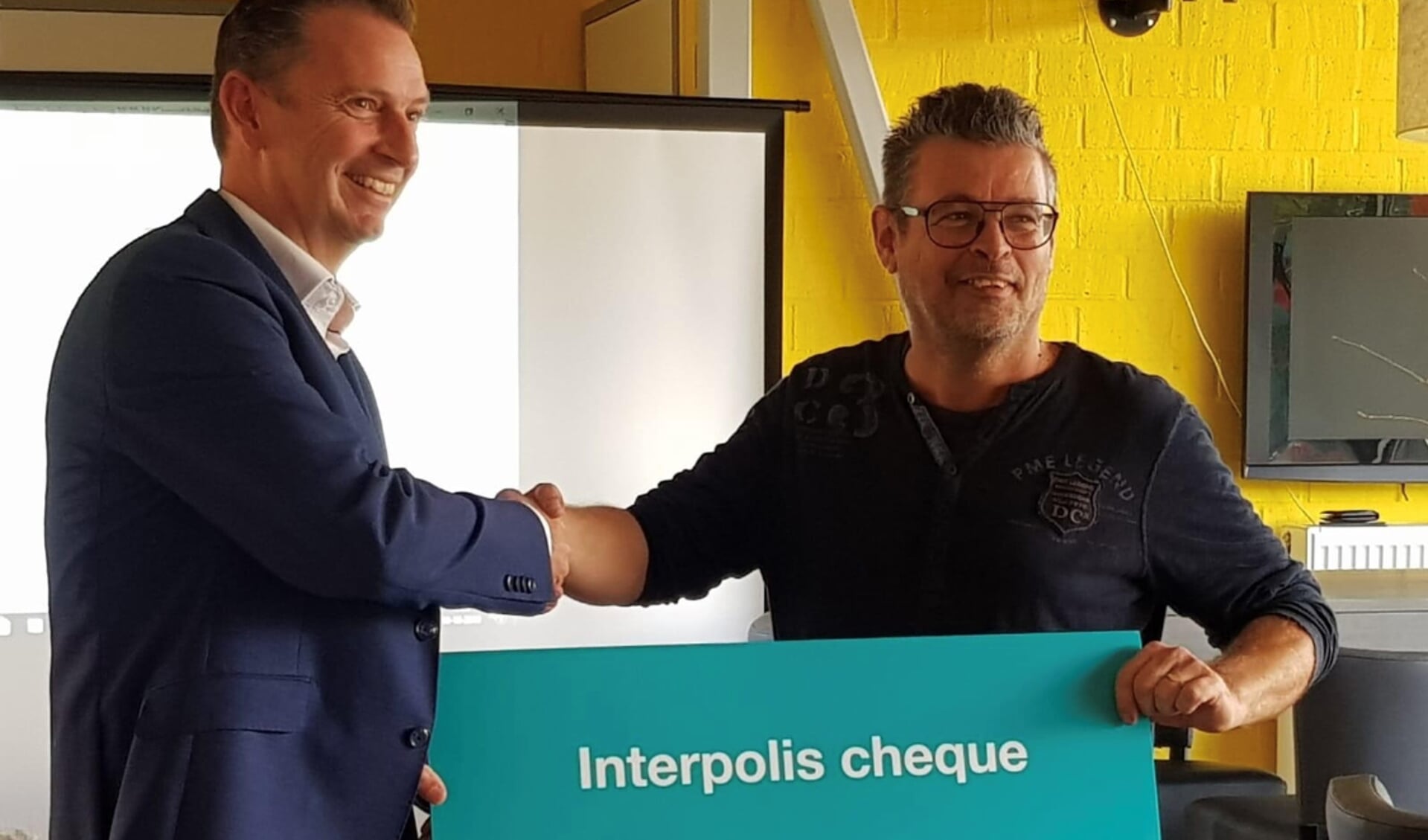 Bas Peeters (rechts) neemt de cheque in ontvangst van Ron van Helden van Interpolis.