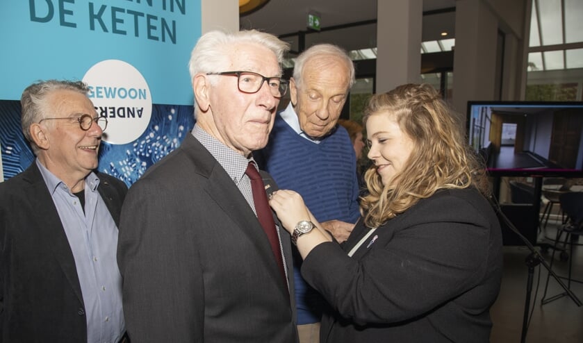 Wethouder Anne Thielen speldt de onderscheiding op bij Harrie Bloemen.