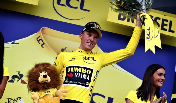 Mike Teunissen straalt op het podium van de Tour de France in de gele trui.