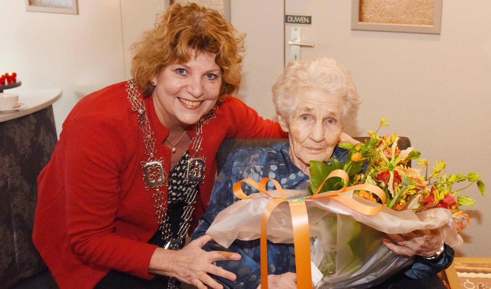 Carla Brugman zet de 100-jarige mevrouw Veldpaus-Thijssen in de bloemetjes. 