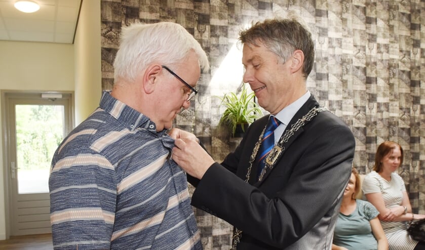 Burgemeester Hans Gilissen speldt Bert Arts de onderscheiding op.