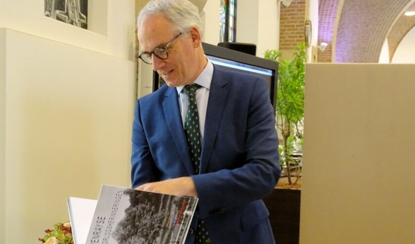 Burgemeester Luc Winants bladert door het boek Venrayse oorlogsherinneringen.