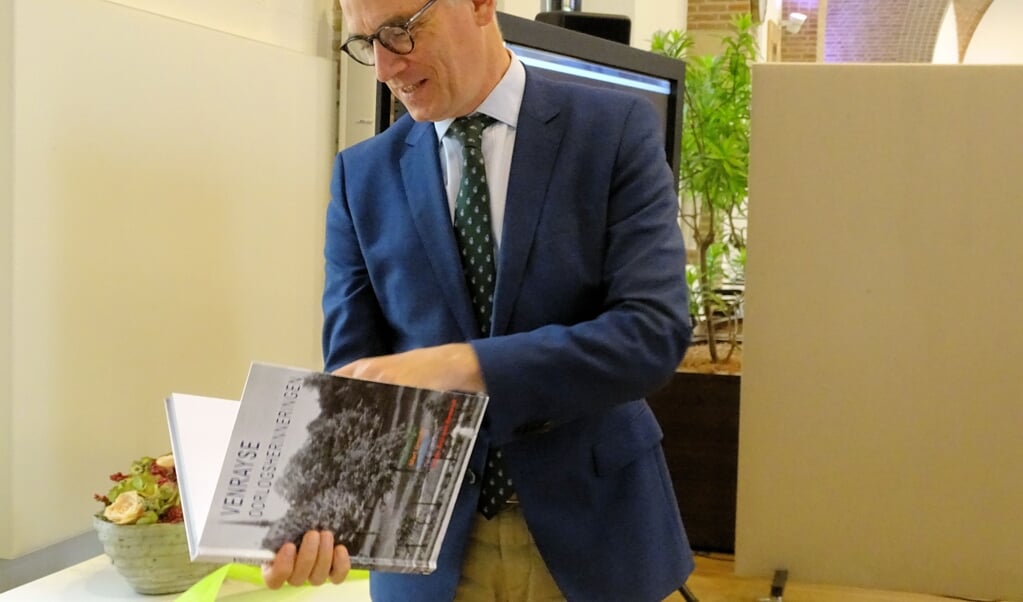Burgemeester Luc Winants bladert door het boek Venrayse oorlogsherinneringen.