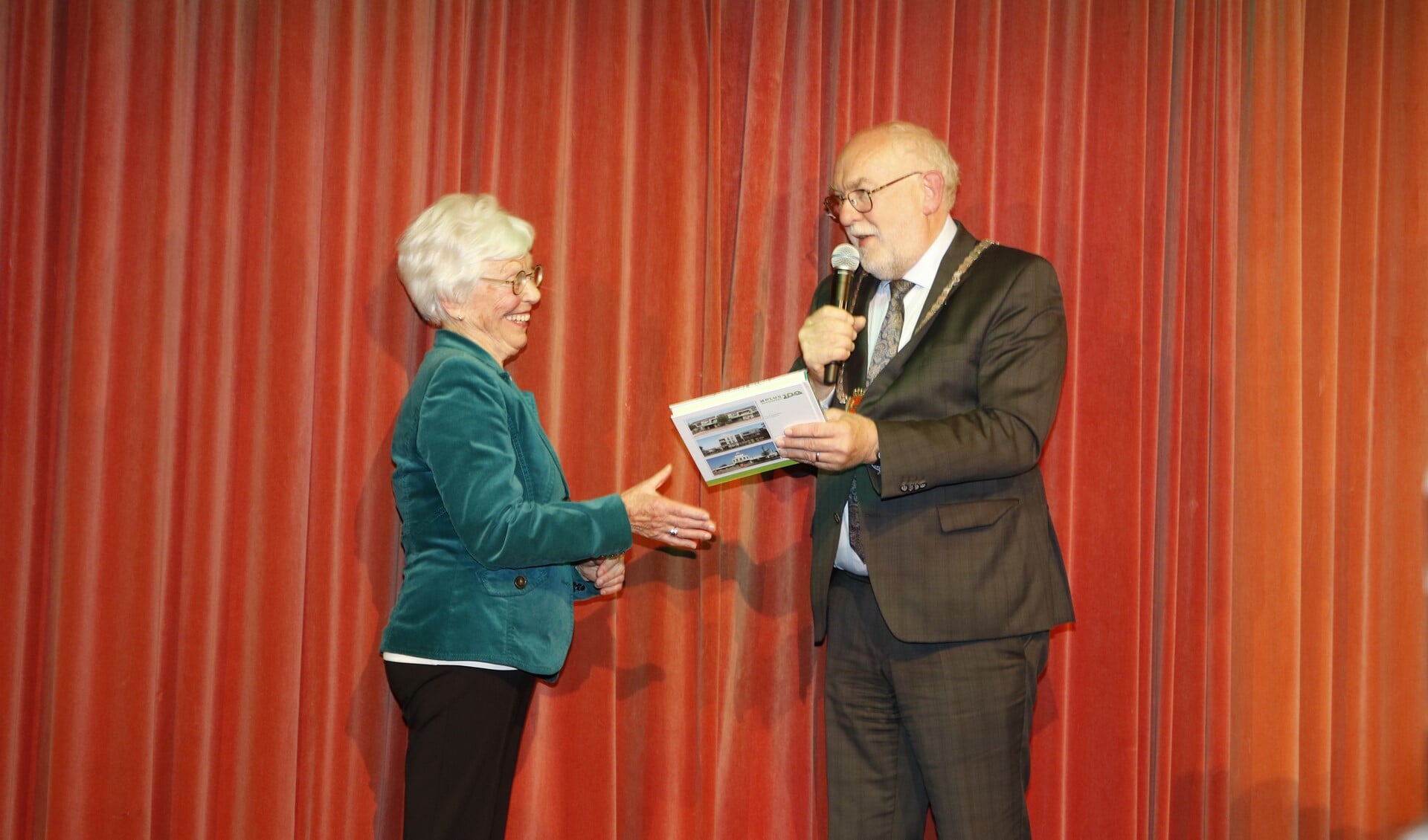 Burgemeester Van Soest overhandigt het jubileumboek aan Mia Verbeeten. 